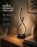 Spiral LED table lamp with tall wavy light strip on black base, glowing warm white