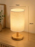 Bedside lamp with textured cylindrical fabric shade and wooden stand base, 13cm wide, 24cm high